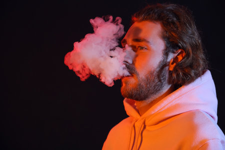 Smoking young man on black backgroundの写真素材