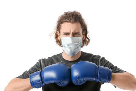 Young man wearing medical mask and boxing gloves on white background. concept of strong immunity