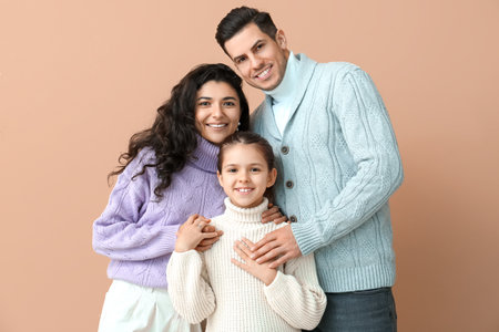 Little girl and her parents in warm sweaters on beige backgroundの写真素材