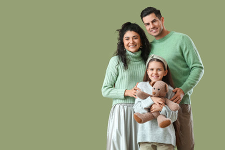 Happy parents with little daughter in warm sweaters on green backgroundの写真素材