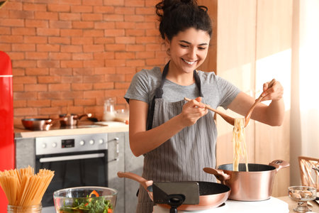Young woman cooking pasta while watching video tutorial in kitchenの写真素材