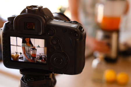 Young woman using blender on display of photo camera in kitchen, closeupの写真素材