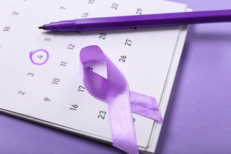 Paper calendar with marked date, awareness ribbon and felt tip pen on color backgroundの写真素材