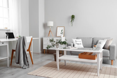 Interior of light living room with coffee table, sofa and workplaceの写真素材
