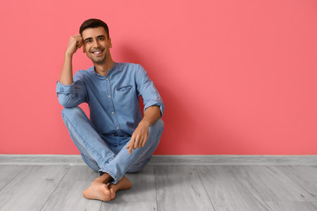 Young barefooted man sitting near pink wallの写真素材