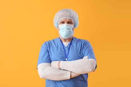 Mature doctor in medical mask on yellow backgroundの写真素材
