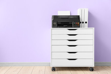 Chest of drawers with printer and folders near color wallの写真素材