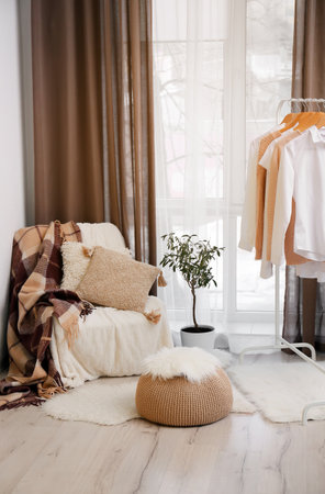 Interior of cozy living room with pouf, chair and clothesの写真素材
