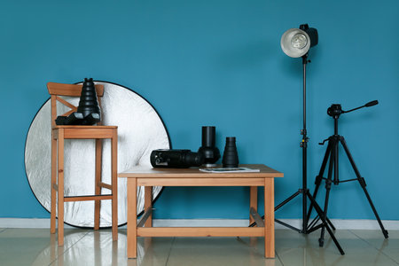 Wooden table and chair with different modern equipment near color wall in photo studio interiorの写真素材