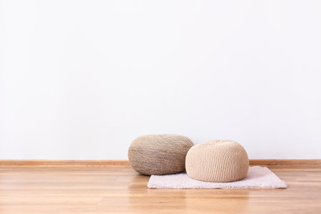 Modern poufs near light wall in room