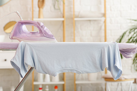 Board with electric iron and t-shirt in laundry roomの写真素材