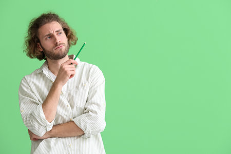 Handsome man with pencil on green background
