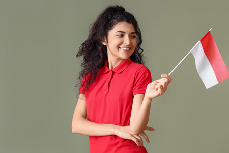 Smiling Asian woman with flag of Indonesia looking aside on color backgroundの写真素材