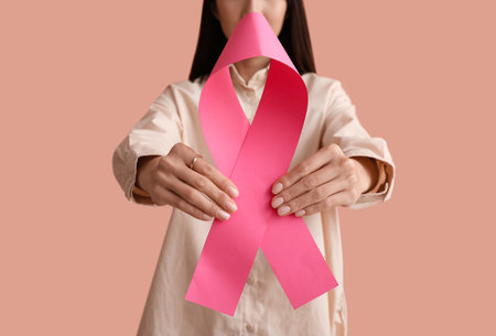 Young woman with pink ribbon on color background. breast cancer awareness conceptの写真素材