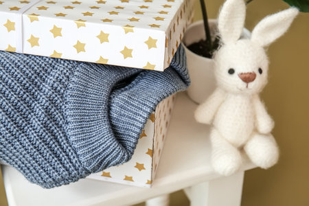Box with knitted sweater for child and toy on stool, closeupの写真素材