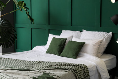 Interior of stylish bedroom with houseplants near green wallの写真素材