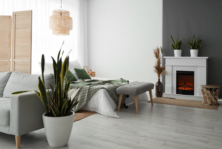 Interior of stylish bedroom with fireplace, soft bench and houseplantの写真素材