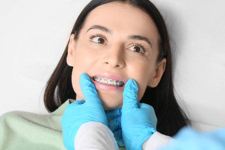 Beautiful woman with dental braces visiting dentist in clinic, closeup