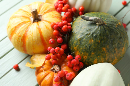 Ripe Halloween pumpkins and rowan berries on light wooden table, closeupの写真素材