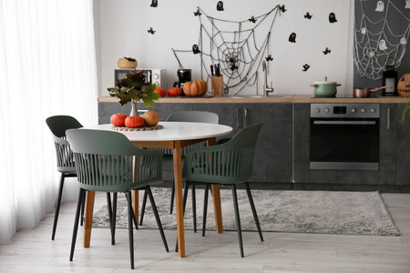 Interior of modern kitchen decorated for Halloween with pumpkins, black counters and dining tableの写真素材