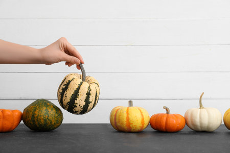 Female hand with Halloween pumpkins on table near light wooden wallの写真素材