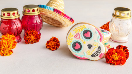 Skull shaped cookies, candles and flowers on white background. El Dia de Muertosの写真素材