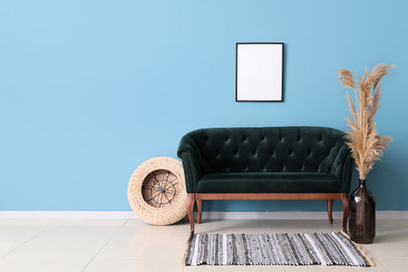 Stylish sofa, blank poster and vase with dry reeds near blue wallの写真素材