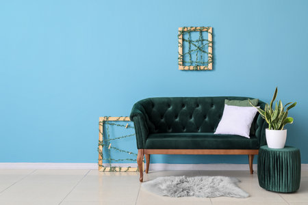 Stylish sofa, pouf and houseplant near blue wallの写真素材