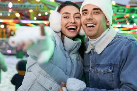 Loving couple in amusement park at winter nightの写真素材