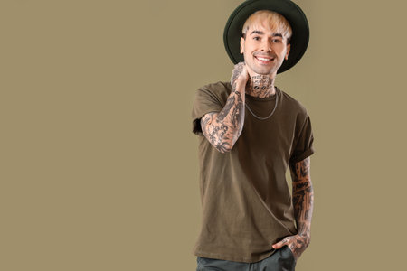 Young tattooed man in hat on green background