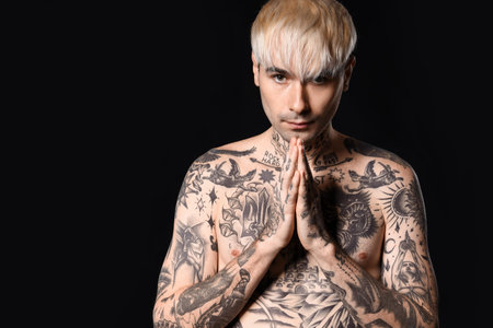 Young tattooed man on dark backgroundの写真素材