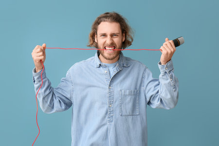 Aggressive young man with microphone on blue backgroundの写真素材
