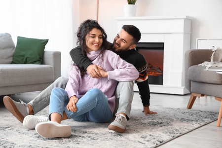Happy young couple wearing warm sweaters at homeの写真素材