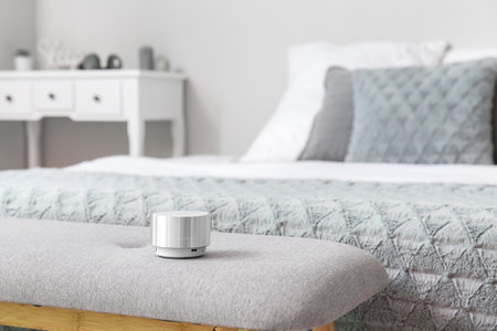 Wireless portable speaker on bench near bed in roomの写真素材