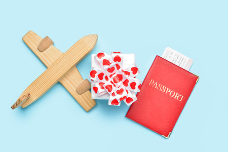 Wooden airplane with gift and passport on blue background. Valentine's Day celebrationの写真素材