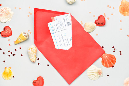 Envelope with tickets, hearts, confetti and seashells on light background. Valentine's Day celebrationの写真素材