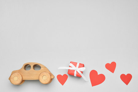 Wooden car with paper hearts and gift on light background. Valentine's Day celebrationの写真素材