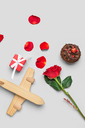 Wooden airplane, gift, rose and muffin on light background. Valentine's Day celebrationの写真素材