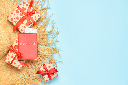 Straw hat with passport and gift boxes on blue background. Valentine's Day celebrationの写真素材