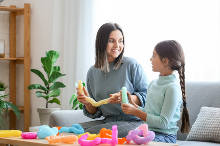 Little girl and her mother playing with Pop Tubes at homeの写真素材
