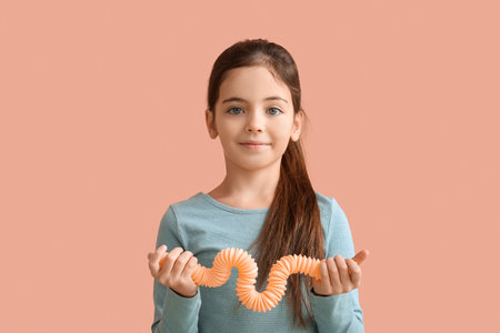 Funny little girl with Pop Tube on pink backgroundの写真素材