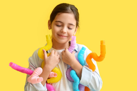 Little girl with Pop Tubes on yellow backgroundの写真素材