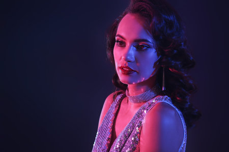 Toned portrait of young woman wearing shiny dress on dark backgroundの写真素材