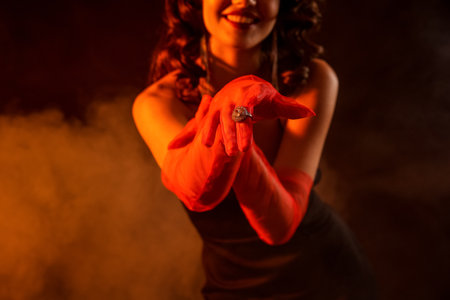 Elegant woman wearing red gloves and stylish jewelry on dark backgroundの写真素材