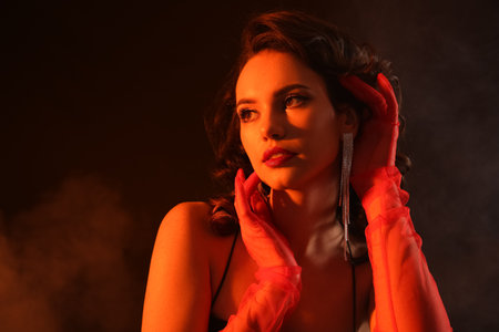 Elegant woman wearing red gloves and stylish jewelry on dark backgroundの写真素材
