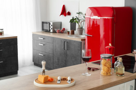 Cheese plate, glass of wine, jar with pasta and oil on table in kitchenの写真素材