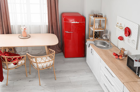 Interior of light kitchen with retro fridge, white counters and dining tableの写真素材