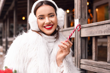 Beautiful woman with candy cane on winter dayの写真素材