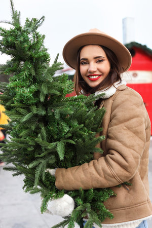 Young woman with small Christmas tree outdoorsの写真素材