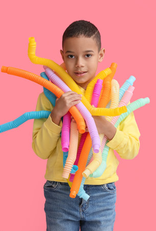 Little African-American boy with Pop Tubes on pink backgroundの写真素材